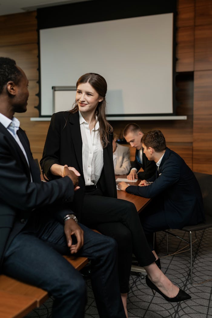 Colleagues shaking hands in a professional office setting, symbolizing teamwork.